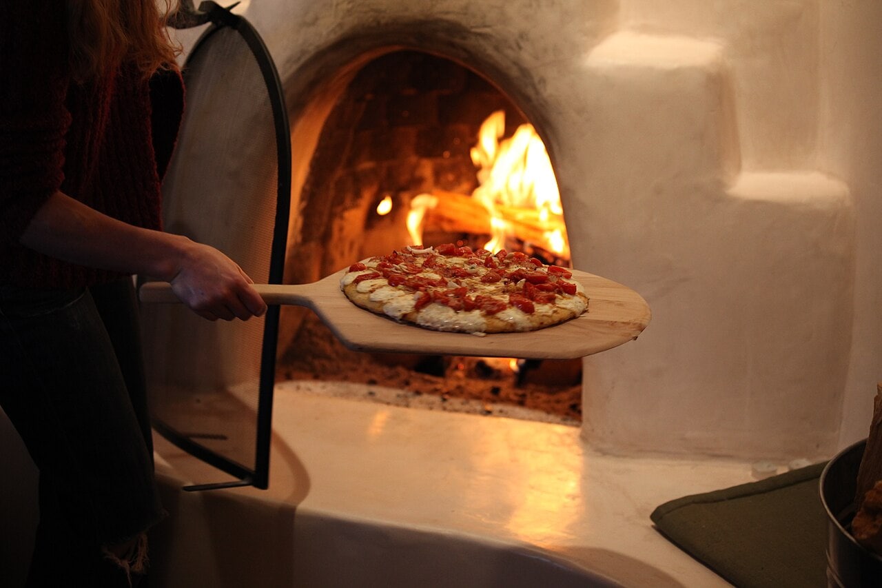 A pizza baking on the floor of a hot wood-fired oven, the style used by Tirana's Neapolitan pizzerias