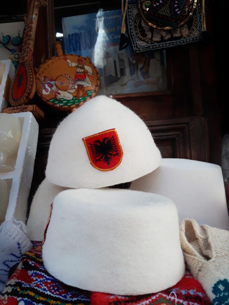 Traditional Albanian plis caps displayed for sale at a craft stall in the Kruja bazaar