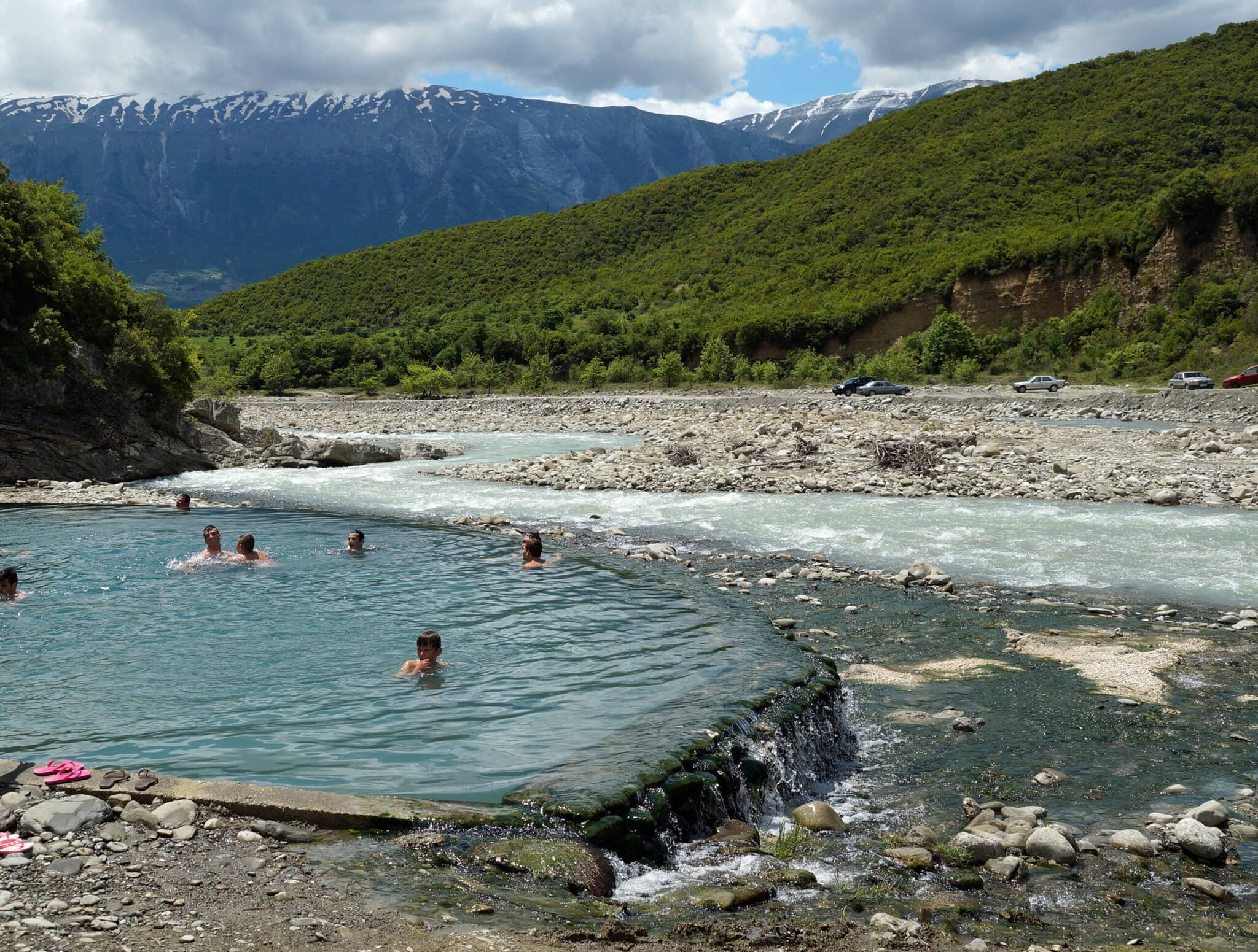Bathers soaking in the main thermal pool at Bënjë with the Lengarica river running past