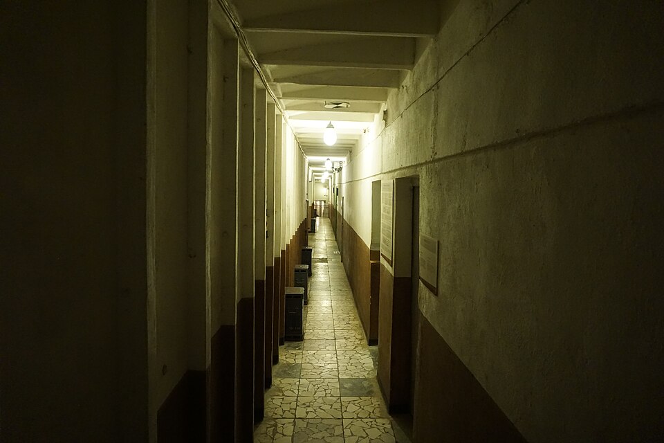 Long underground corridor lined with numbered rooms inside Bunk’Art 1