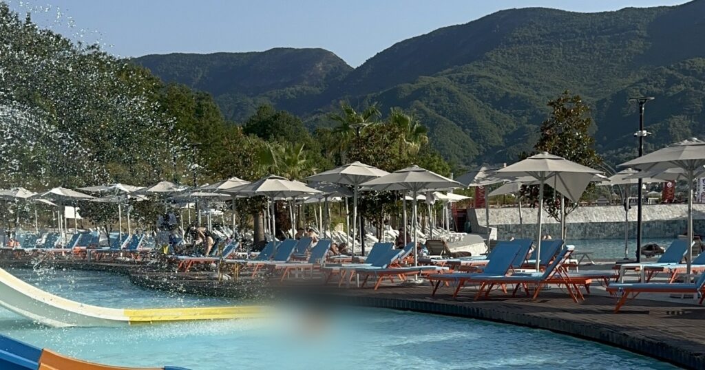 Equos aquapark near Tirana: kids slides, sun loungers and the Petrele hills behind, July 2026