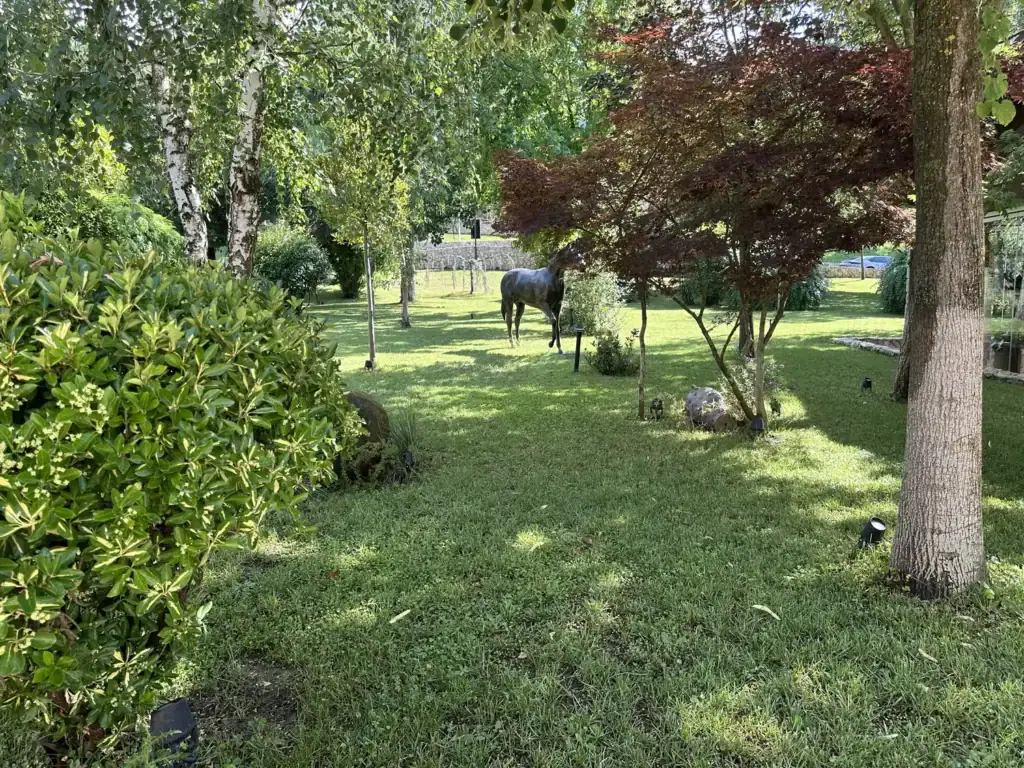 Landscaped garden at Farm 88 near Tirana with mature trees and a life-size bronze horse sculpture