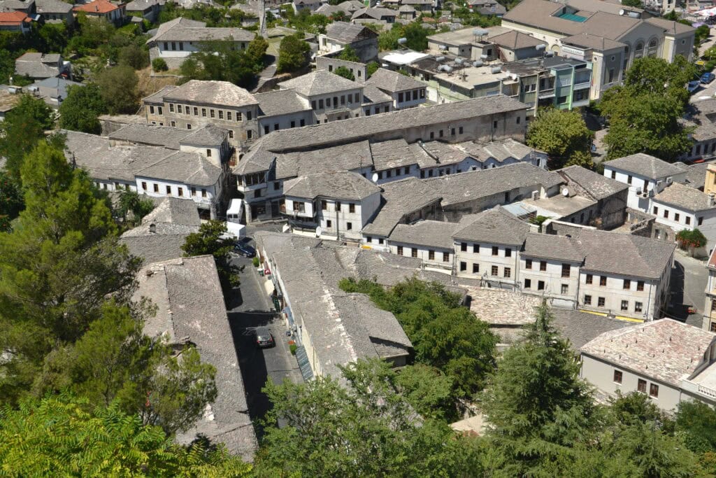 Elevated view of Gjirokastra's densely packed stone-roofed houses climbing the hillside below the fortress