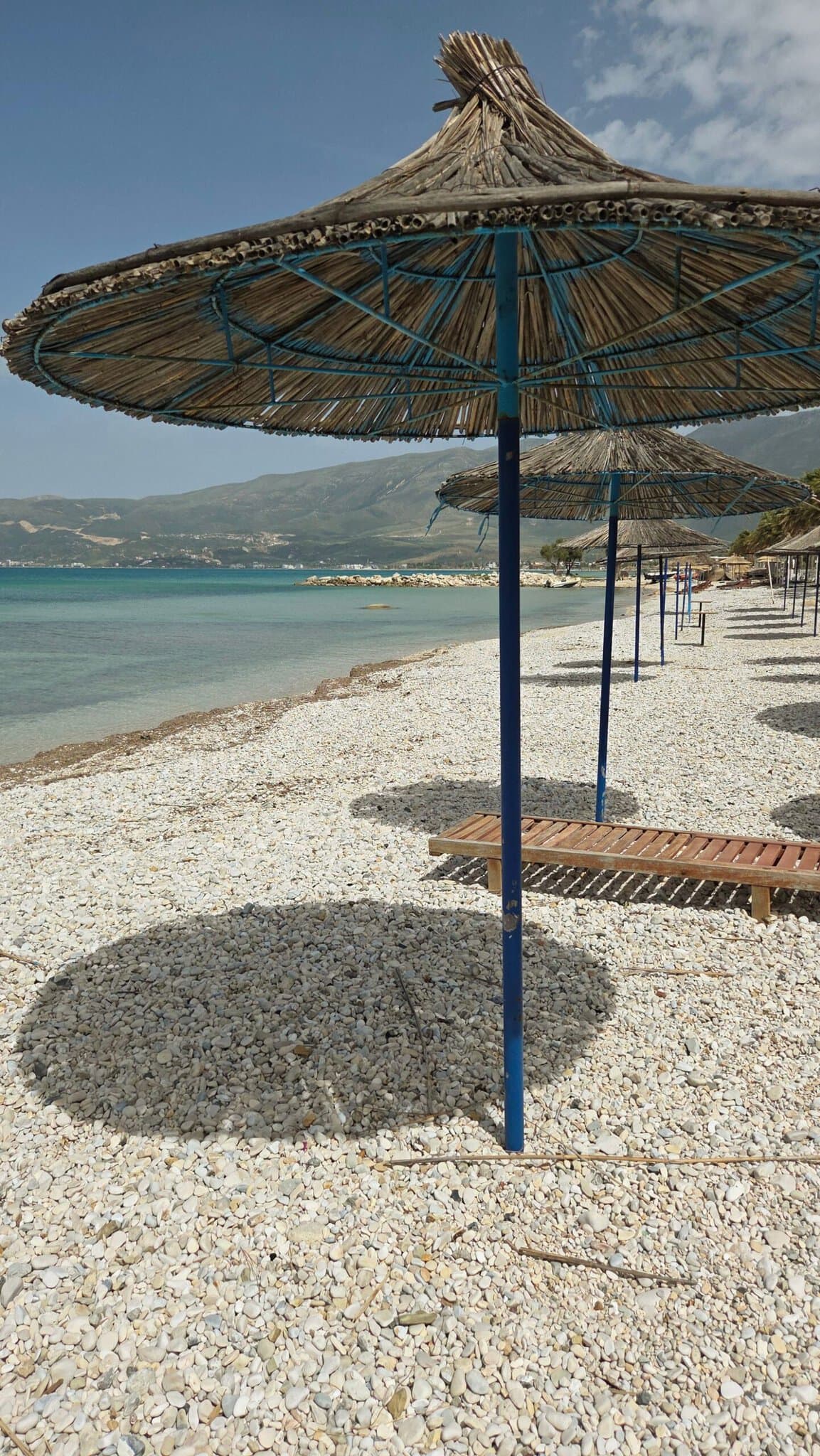 A pebble beach with straw umbrellas along the seafront in Vlorë, Albania