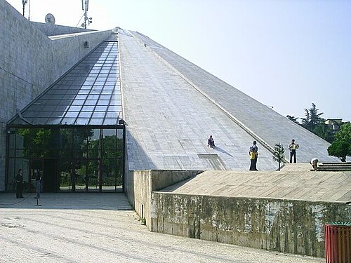 Children sliding down the sloped concrete sides of the ruined Pyramid of Tirana in 2012, watched by other kids at the base
