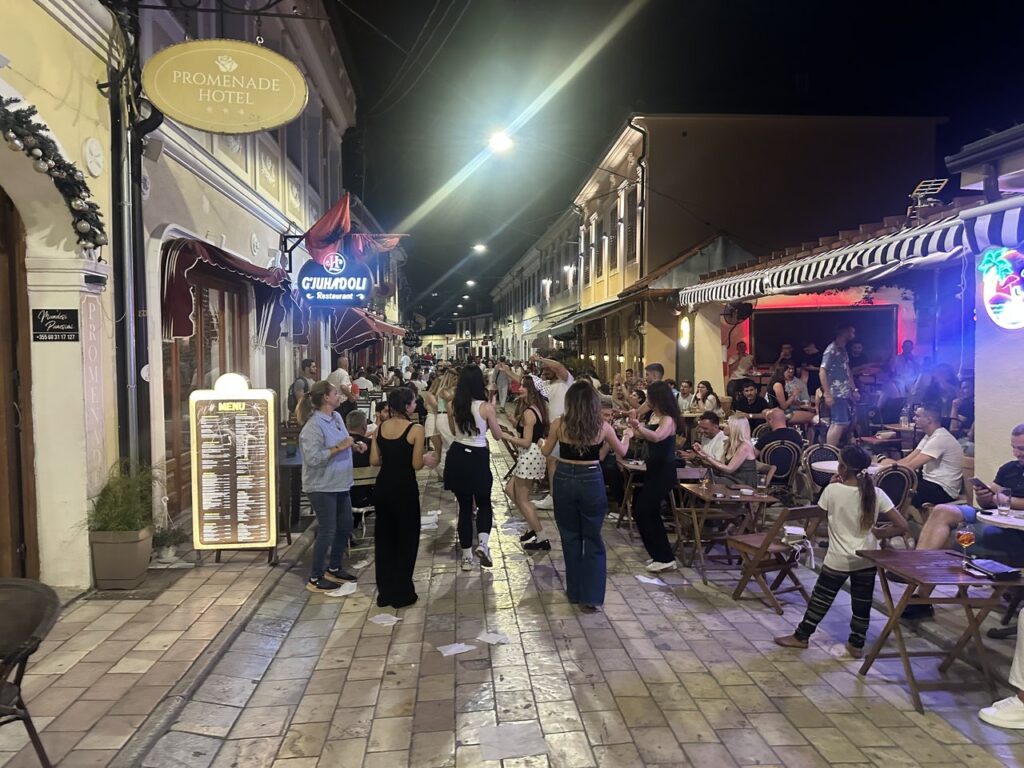The old bazaar of Shkodra at night, full of people with cafe tables and string lights