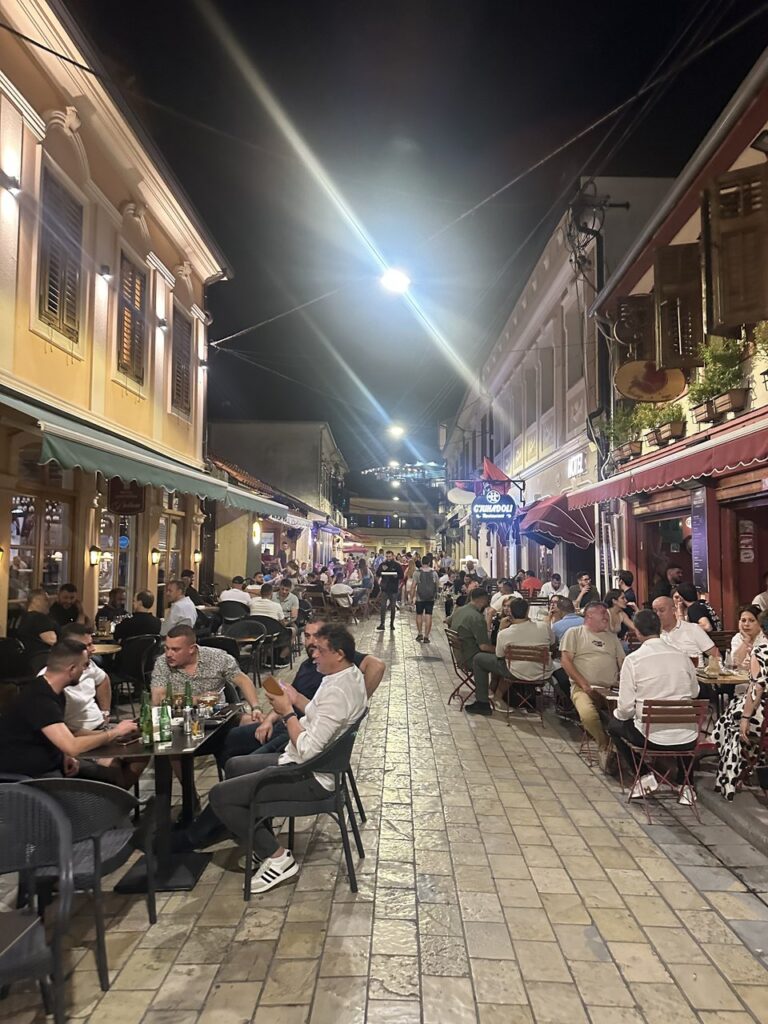 Diners at outdoor restaurant tables in the Shkodra old bazaar in the evening