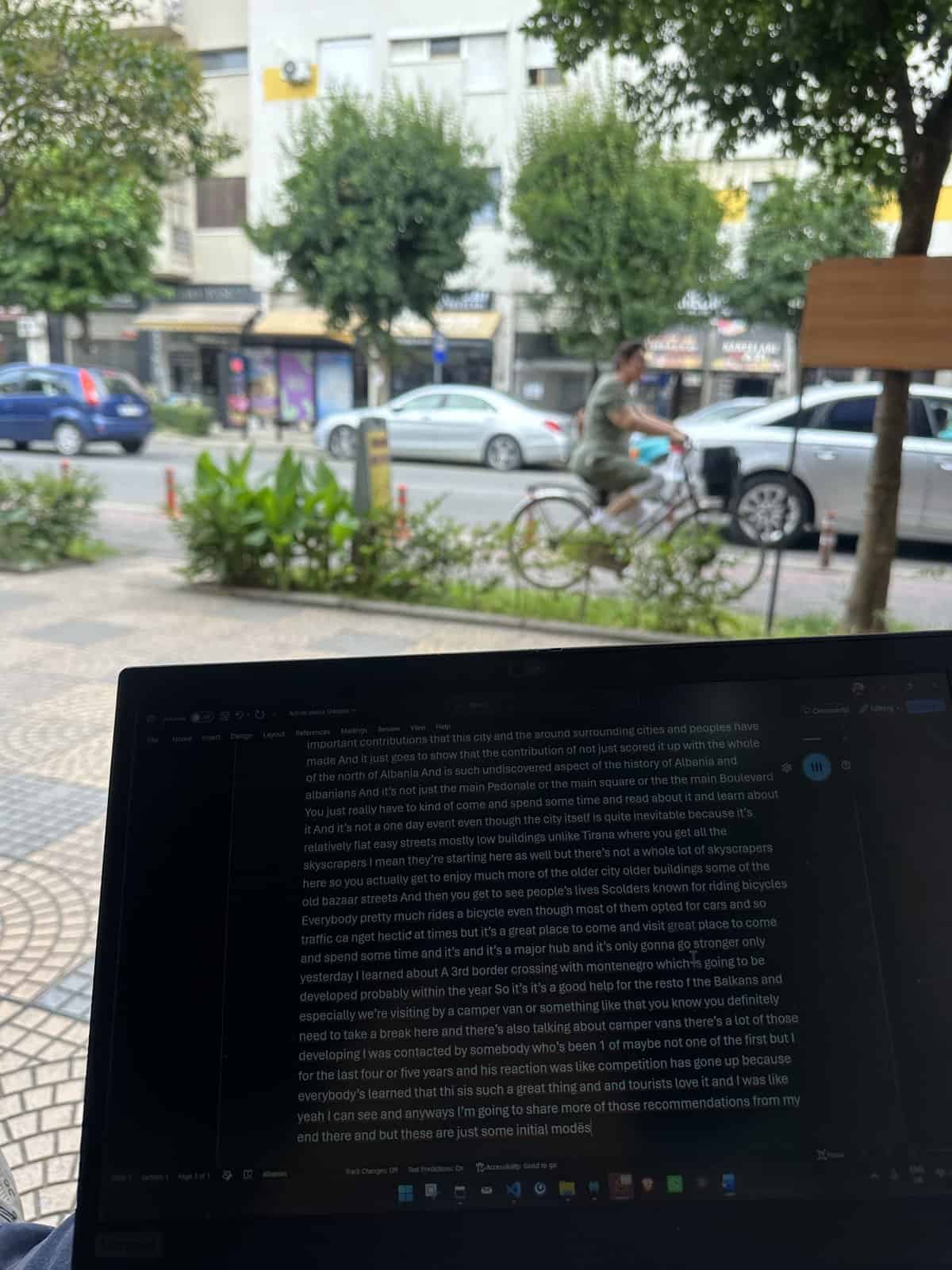 A cyclist passing a pavement cafe table in Shkodra on a quiet morning street
